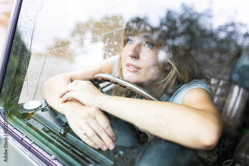 Thoughtful beautiful woman looking through car window photo