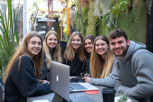 photo of a team of young business men women working in teamwork on their computer in an office smiling into the camera