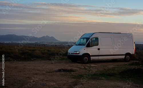 A camper van parked in a scenic wilderness during sunset, ideal for outdoor camping adventures.