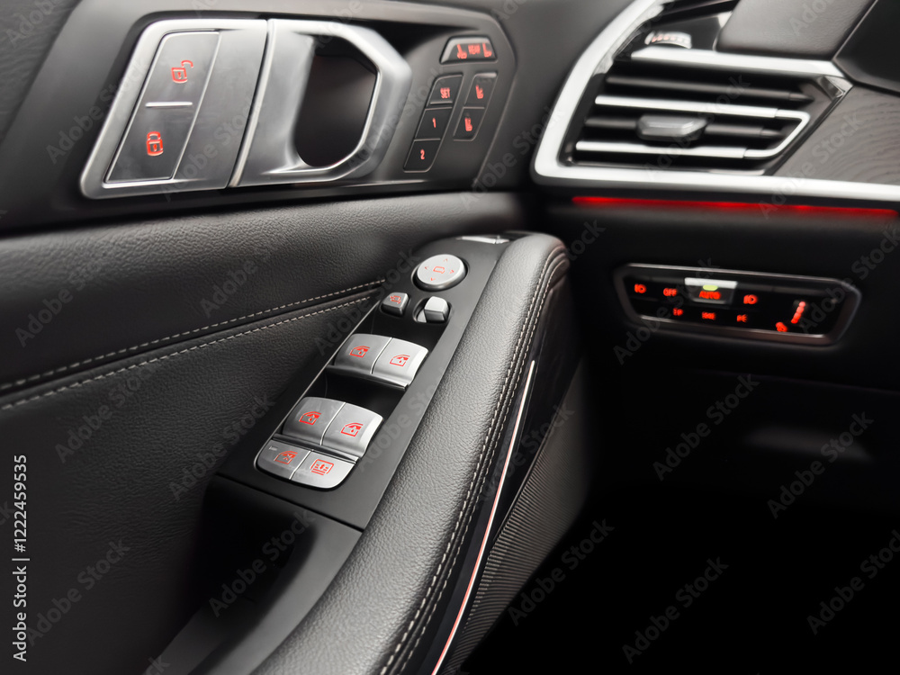 Door handle with power window control buttons. Black perforated leather interior with stitching. Modern car black leather interior details. Door handle with power window control buttons. Black perforated leather interior with stitching. Modern car black leather interior details.