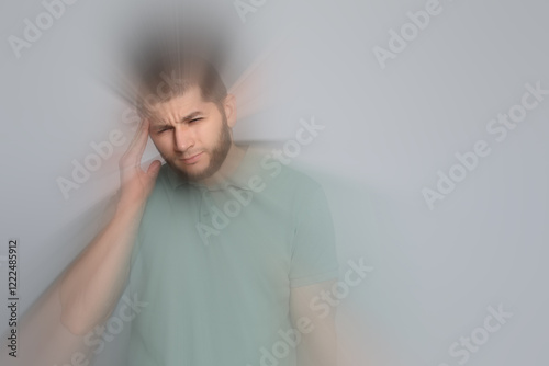 Man suffering from headache and dizziness on grey background photo