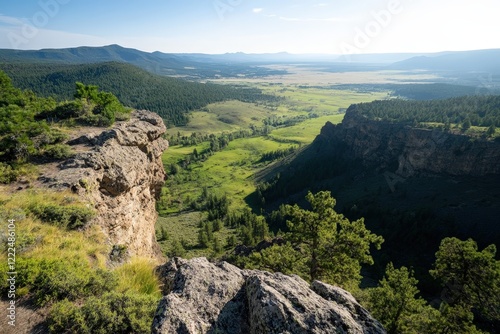 A stunning view from atop a rugged cliff, capturing the lush green valley below and the expansive sky, offering an inspiring perspective of nature's raw beauty and grandeur. photo