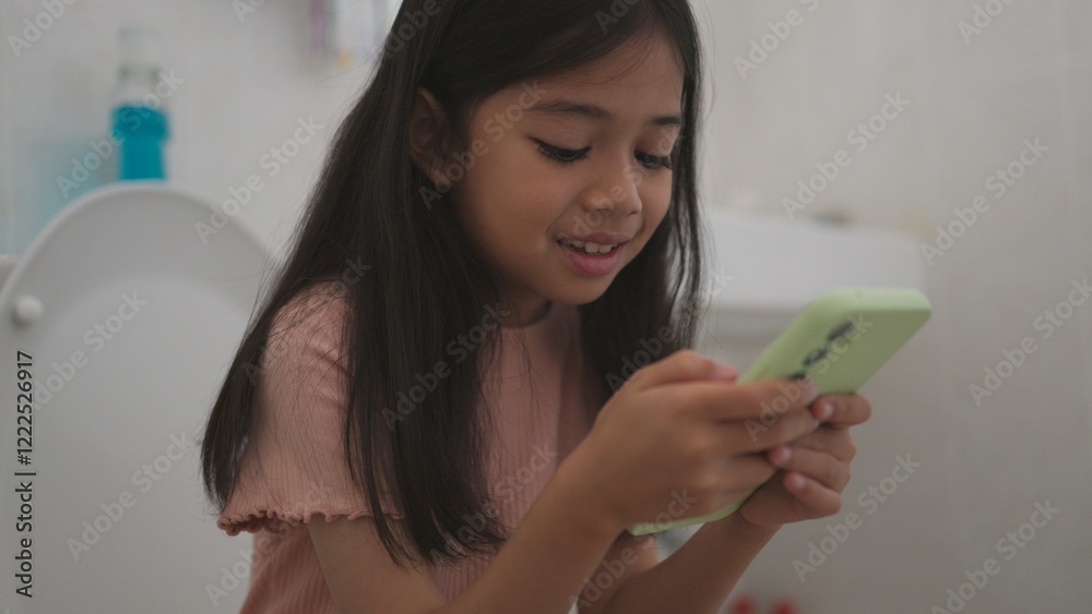 child sitting on the toilet holding the tablet.child addicted smartphone concept child sitting on the toilet holding the tablet.child addicted smartphone concept