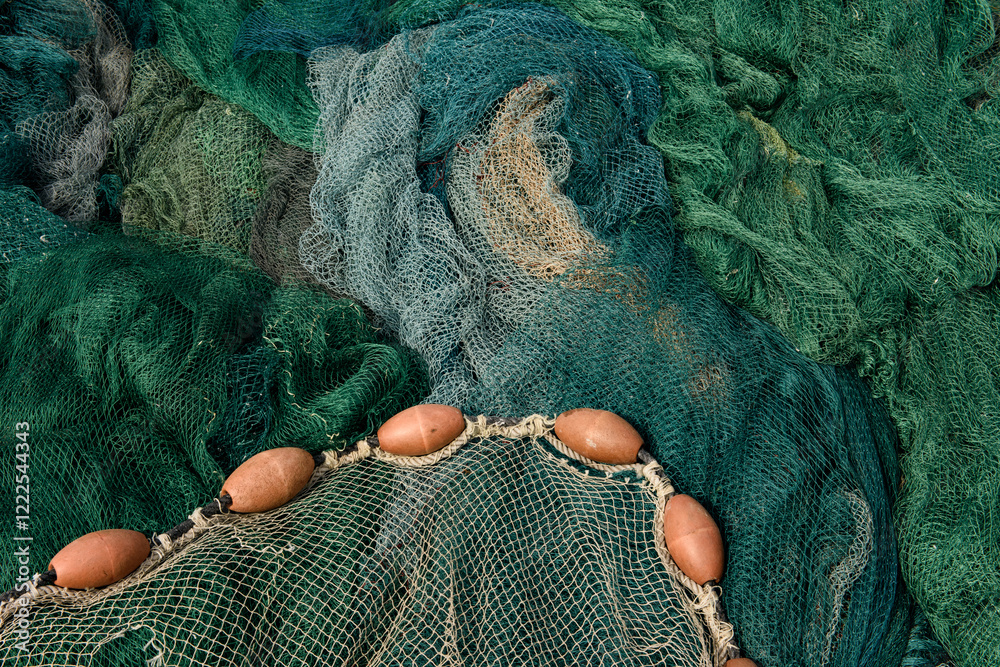 An abstract tangle of large, green and blue fishing nets and buoys, laying on a dock in the historic Jaffa Port, Israel. An abstract tangle of large, green and blue fishing nets and buoys, laying on a dock in the historic Jaffa Port, Israel.