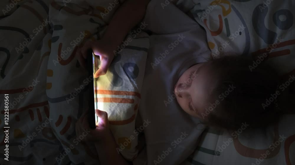 A little girl is playing mobile games on her phone. Addiction to online video games on a smartphone. The concept of children's dependence on technology.
