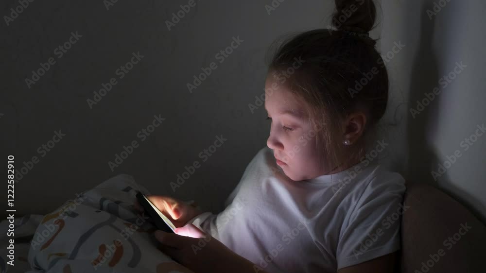 A little girl is playing mobile games on her phone. Addiction to online video games on a smartphone. The concept of children's dependence on technology.
