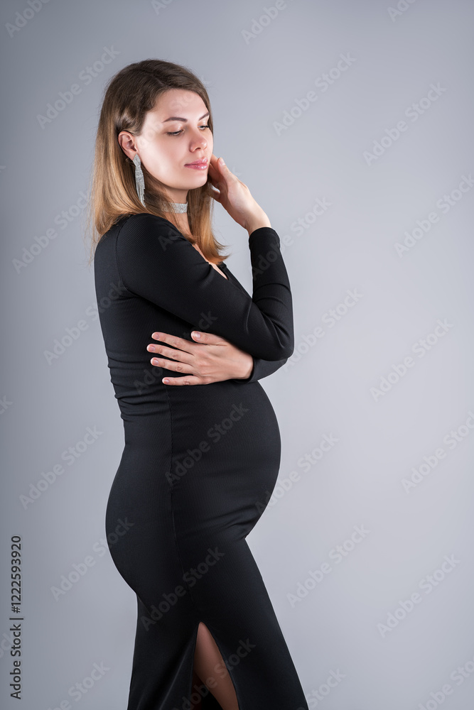 Beautiful pregnant woman in black dress on gray background, maternity clothes, pregnancy photoshoot