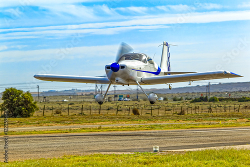 Small blue and white single engine, tail-dragger aerobatic aircraft manufactured from a kit taking off from airstrip in the Western Cape, South Africa photo