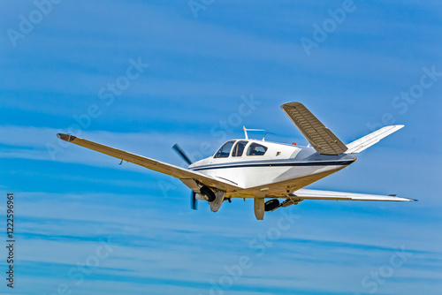 Rear view of six-seat white aircraft with black and blue stripes with unusual V shaped tail against blue sky in the Western Cape, South Africa