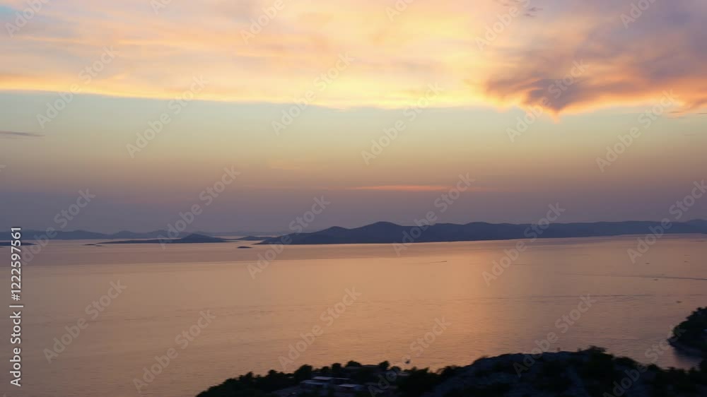 Scenic panoramic view of the calm sea and distant hills at sunset with soft golden and pink hues in the sky, capturing the serene beauty of nature and peaceful coastal landscapes. High quality 4k foot Scenic panoramic view of the calm sea and distant hills at sunset with soft golden and pink hues in the sky, capturing the serene beauty of nature and peaceful coastal landscapes. High quality 4k foot