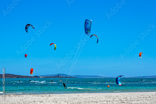 Photography Enthusiastic kite surfers with brightly coloured kites surfing on the lagoon at