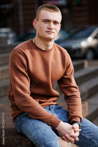 A Young Man Posing in Casual Urban Attire on Steps in Daylight photo