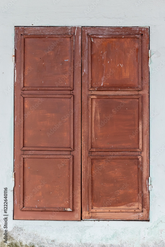 Closed rustic wooden window shutters on aged wall Closed rustic wooden window shutters on aged wall