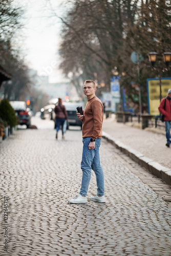 Wallpaper Mural Young man on a cobblestone street holding a coffee cup Torontodigital.ca