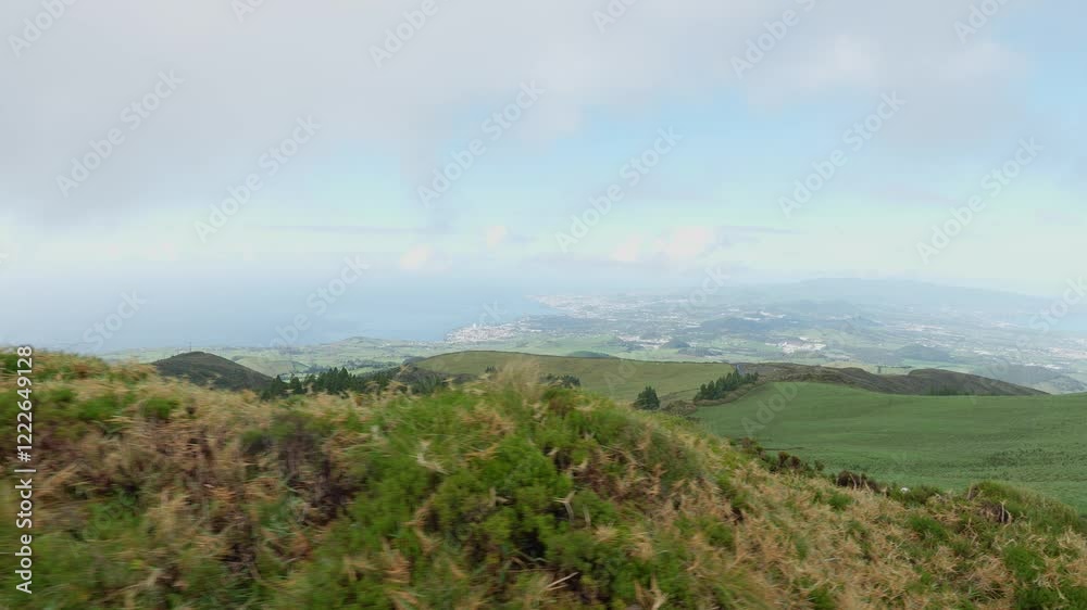 green grassy hillside under cloudy sky with vast fields in the background at the Sao Miguel island green grassy hillside under cloudy sky with vast fields in the background at the Sao Miguel island