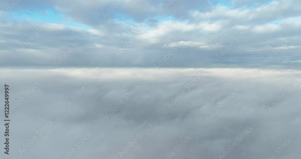 Aerial view from a drone flying through the dense white clouds in blue sky at the daytime