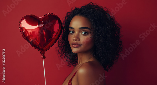 a beautiful woman holding a heart-shaped balloon against a red background. Valentines day concept
