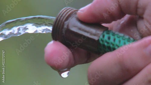 Close-up of a hand holding water flowing from a garden hose, symbolizing resource availability, sustainability and the importance of hydration in outdoor environments. Climate change. Global warming. 