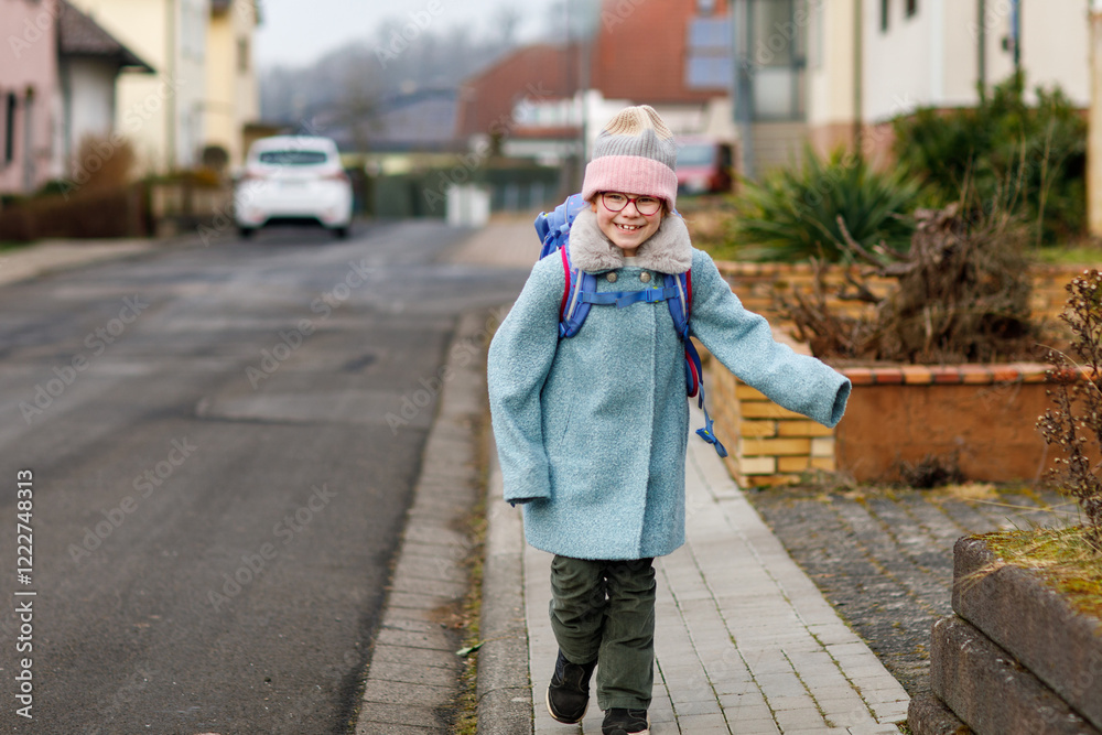 Cute little girl o the way to or from school. Healthy happy child with eyeglasses walking to primary school. Smiling child with schoolbag on the city street, outdoors. Back to school. Cute little girl o the way to or from school. Healthy happy child with eyeglasses walking to primary school. Smiling child with schoolbag on the city street, outdoors. Back to school.