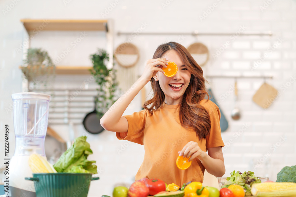 cheerful young woman having fun while cooking in the kitchen two hands holding pieces of orange slices at face,healthy food,vitamin,beauty,health