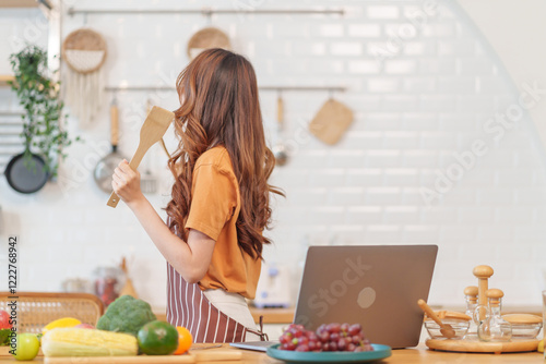 cheerul young asian woman cooking healthy food show on live streaming by laptop online in modern kitchen photo