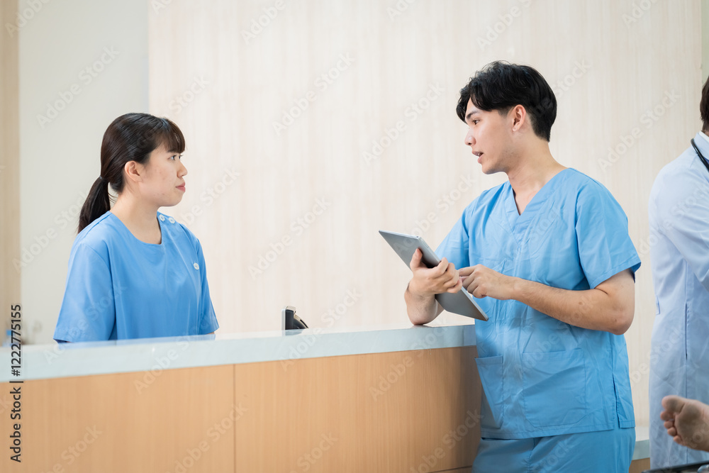 Asian doctor trainee in scrubs engage friendly discussion. Professionals in hospital use tablet technology in patient care, Smiling nurses in blue uniform attention to health care information Asian doctor trainee in scrubs engage friendly discussion. Professionals in hospital use tablet technology in patient care, Smiling nurses in blue uniform attention to health care information