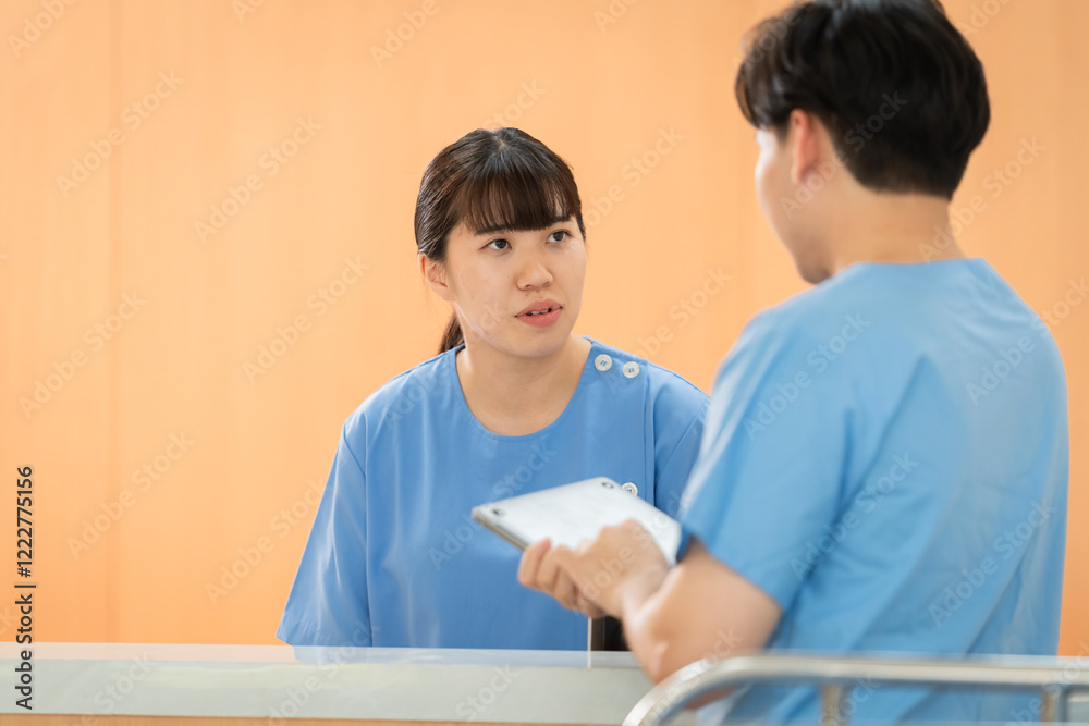 Asian doctor trainee in scrubs engage friendly discussion. Professionals in hospital use tablet technology in patient care, Smiling nurses in blue uniform attention to health care information Asian doctor trainee in scrubs engage friendly discussion. Professionals in hospital use tablet technology in patient care, Smiling nurses in blue uniform attention to health care information