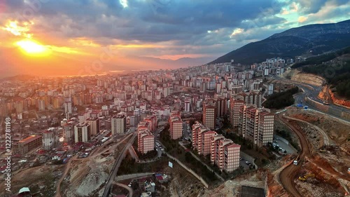 The video shows a wide cityscape at sunset with completed multi-story residential buildings in the foreground. The housing appears to be part of a large-scale residential construction project. photo