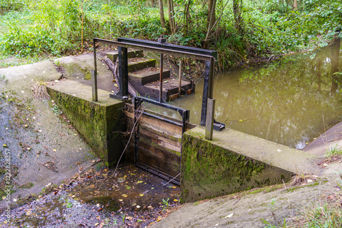 wooden adjustable stop log on a small concrete weir on the canal