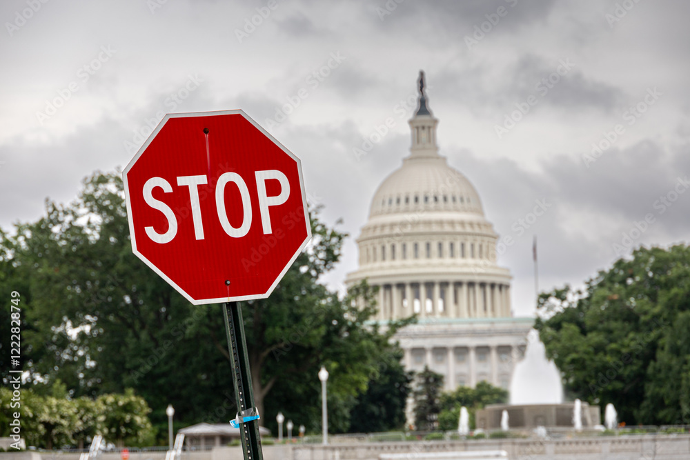 A stop sign juxtaposed against the US Capitol dome, symbolising authority, governance, and safety amidst an overcast day. Stop sign in front of US Captiol.