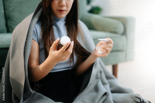 Young Asian woman suffering from flu symptoms, covered with a blanket on a sofa. Concept of illness, healthcare,