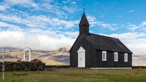 Picturesque black church set against Icelandic mountains under a bright blue sky. Budir, Iceland photo