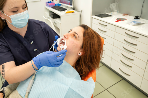 Tablou pe pânză Dentist performing oral examination on patient with mouth retractor in modern cl