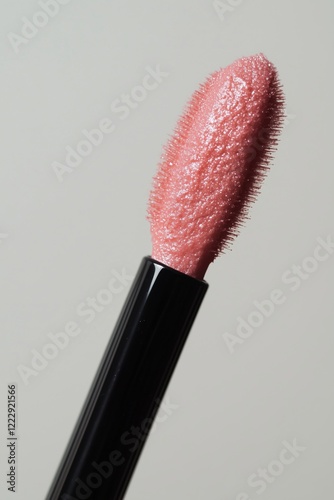 Close-up of a lip gloss applicator with shimmery pink product.