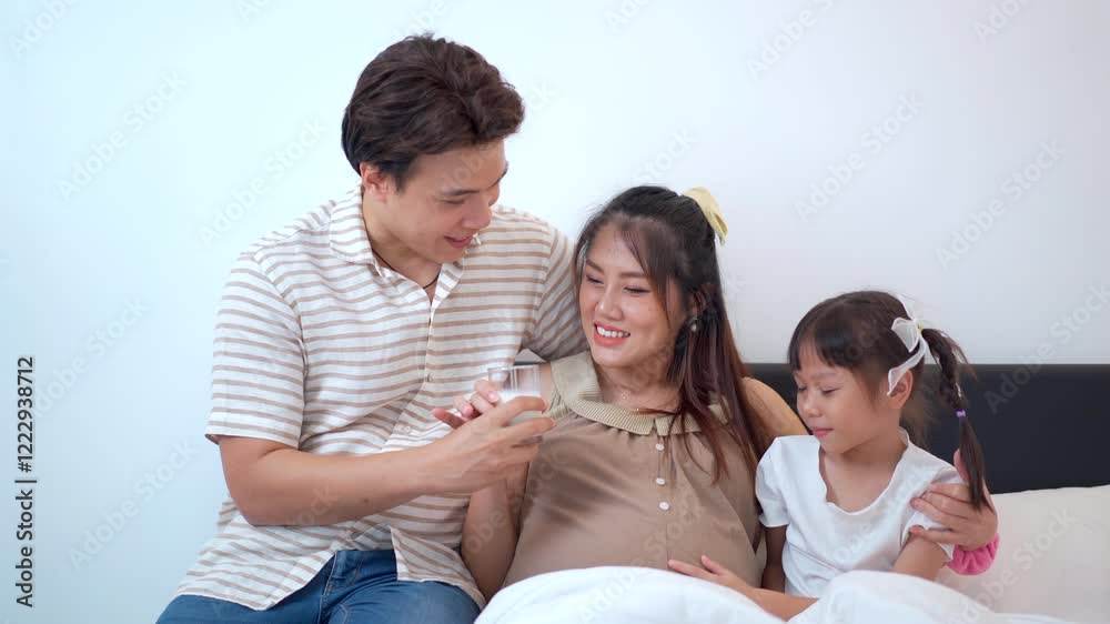 Asian family with father, pregnant mother, and daughter are relaxing and talking together. Asian family with father, pregnant mother, and daughter are relaxing and talking together.