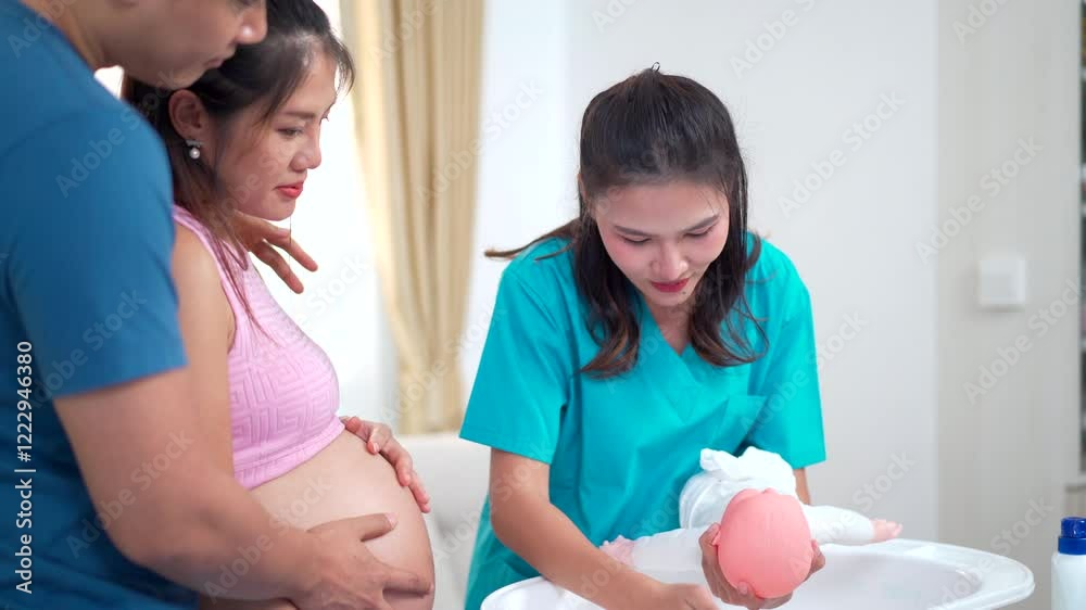 Asian husband and his pregnant wife are learning how to bathe a newborn baby, guided by a nanny nurse. Asian husband and his pregnant wife are learning how to bathe a newborn baby, guided by a nanny nurse.