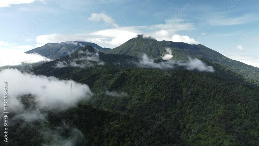 Misty white clouds roll across Mount Gede Pangrango, Indonesia, the peaks of the mountain are bright and dark blue. Forests and mountains in the natural tourist area, Puncak Bogor. Misty white clouds roll across Mount Gede Pangrango, Indonesia, the peaks of the mountain are bright and dark blue. Forests and mountains in the natural tourist area, Puncak Bogor.