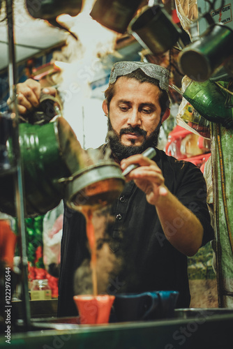Pakistani Afghani street vendor pouring hot chai tea into cups in his roadside tea stall