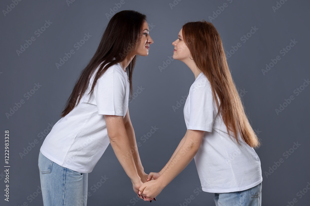 Beautiful mother with teenage daughter on grey background Beautiful mother with teenage daughter on grey background