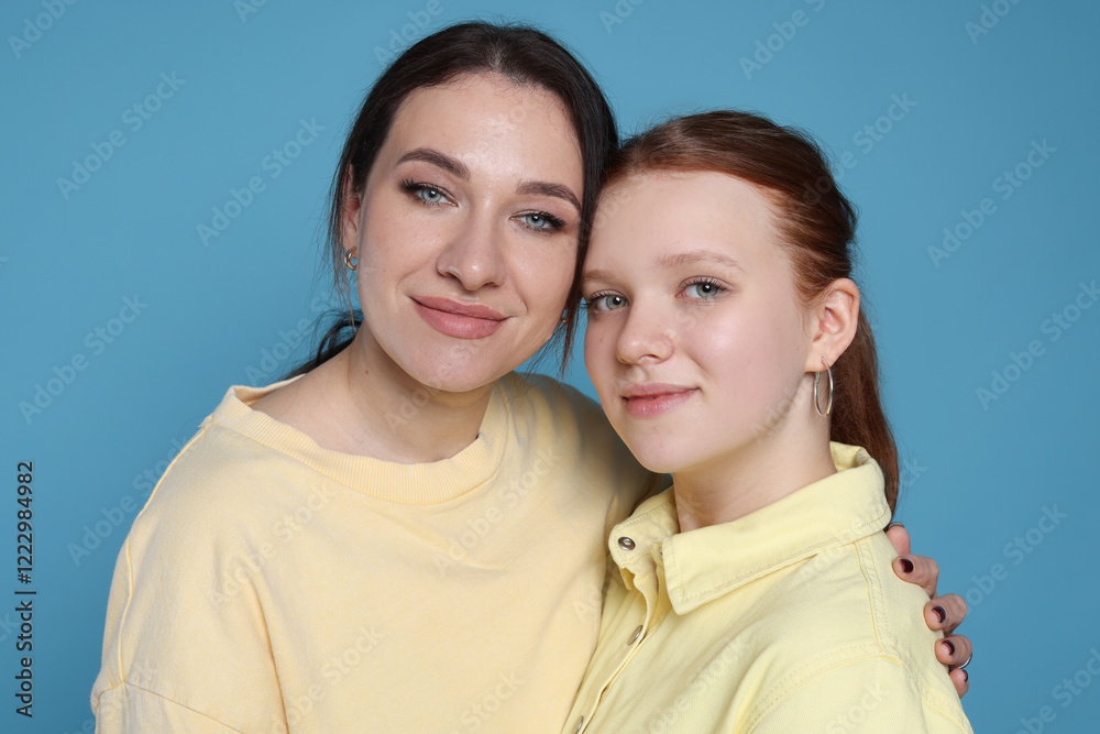 Obraz premium Portrait of beautiful mother with teenage daughter on light blue background