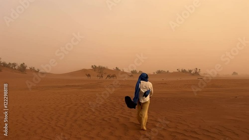 Berber Arab man walking in large desert with camel landscape in background