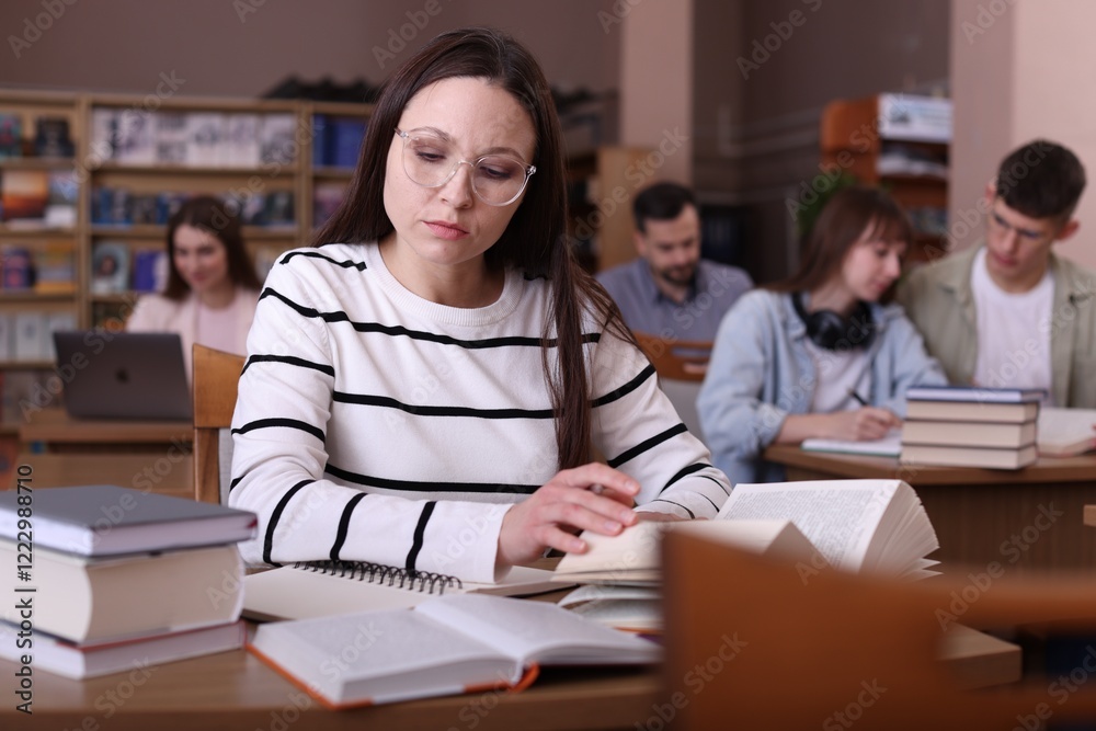 Beautiful woman reading book at desk in public library Beautiful woman reading book at desk in public library