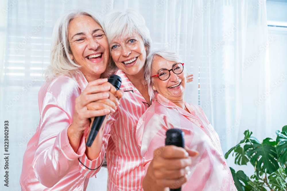 Beautiful senior women having funny pajama party at home - Group of cheerful elderly female friends having fun at home dancing and singing, concepts about old people, lifestyle and quality of life