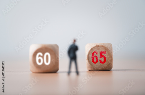Defocus of businessman miniature figure with 60 and focus on 65 for extend of retirement period from 60 years old to 65 years old , Aging society concept.