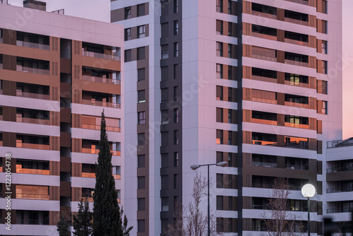 This image showcases a contemporary residential complex reflecting sunset hues, signifying modern urban living and the connection between architecture and nature's beauty. photo