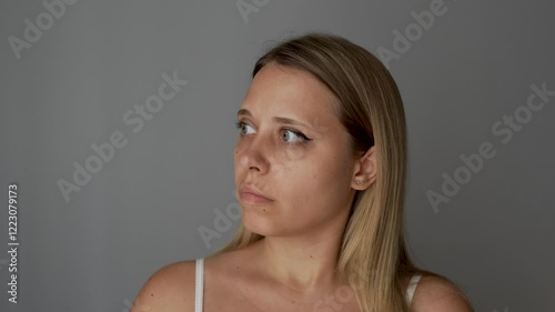 Young blonde woman opens her eyes wide, startled by the sudden noise on a dark grey background. Sudden reaction to an external stimulus, neurosis, misophobia, fear, fright. Highly sensitive person