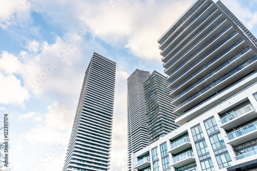 Modern residential high-rises stand tall against a partly cloudy sky, showcasing sleek architectural design and city living.