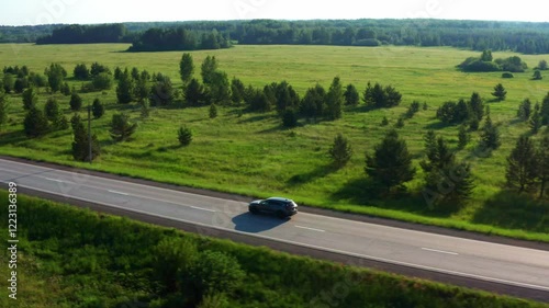 Aerial view of a car driving on the road in a field