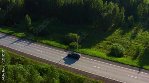 Aerial view of a car driving on the road in a field