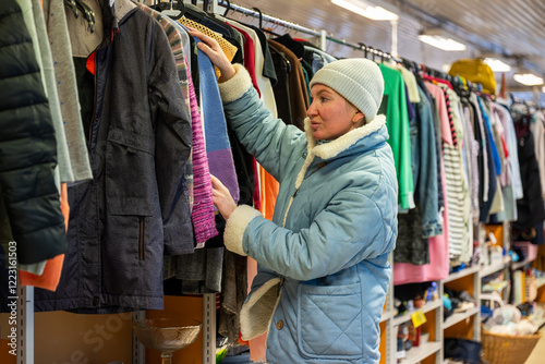 Woman browsing clothes in a thrift shop. Second hand concept	
